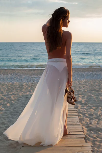 Dziewczyna spacerująca po plaży o zachodzie słońca — Zdjęcie stockowe