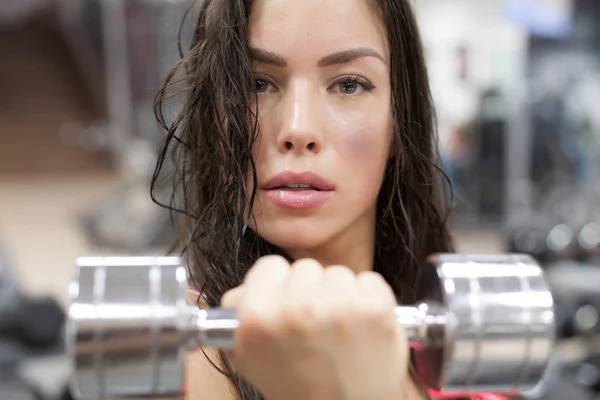 Joven mujer haciendo ejercicio con pesas en un gimnasio — Foto de Stock