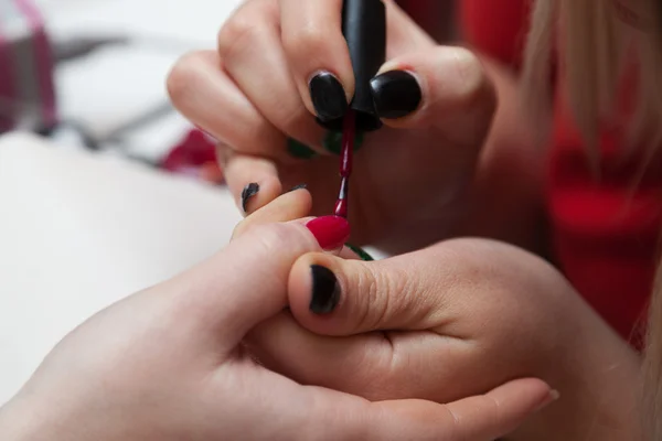 Menina coloca um verniz de unhas em seu cliente — Fotografia de Stock