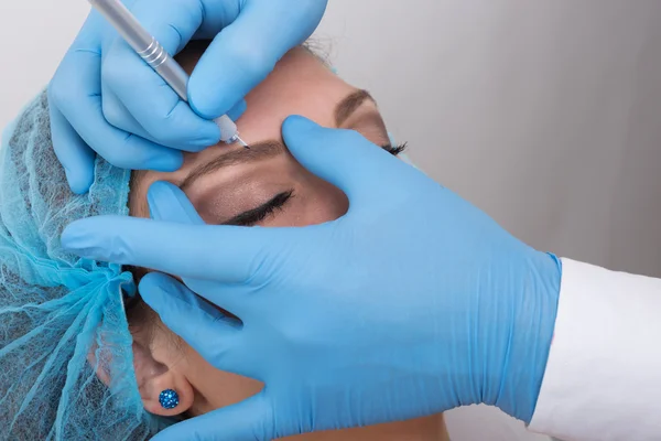 Jonge vrouw krijgen een permanente wenkbrauw make-up behandeling — Stockfoto