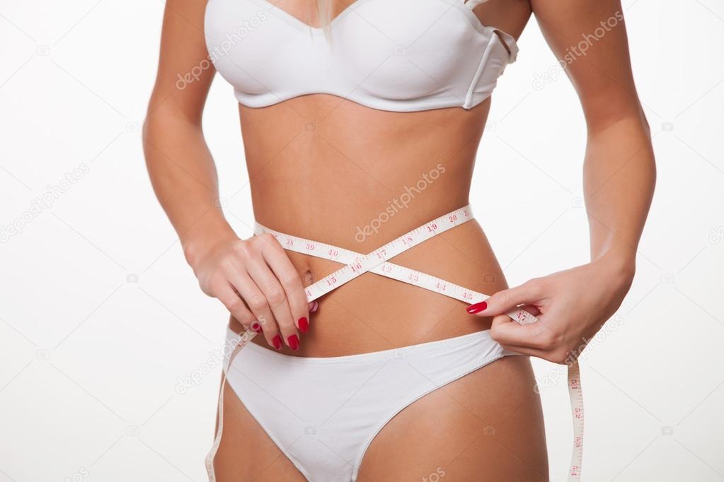 Young woman in white underwear measuring waist with a tape