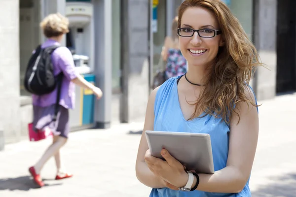 Jonge vrouw met een tablet op straat — Stockfoto