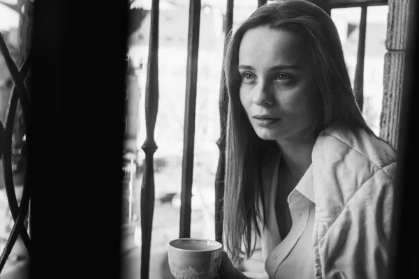 Portrait of happy young woman, happy drinking coffee, morning tea on the balcony, pleasant morning. Selective focus. Black and white photo