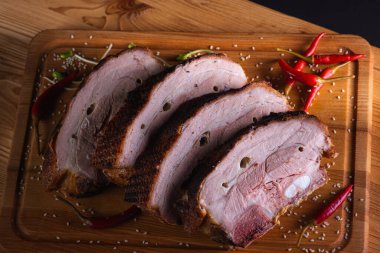 Lezzetli, sulu ve güzel kokulu domuz eti, siyah arka planda ahşap bir tahtada pirzola, acı kırmızı biber ve baharatlar. Lezzetli et konsepti