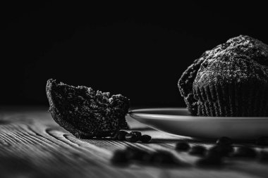 Siyah beyaz fotoğraf, sade anahtar, ev yapımı lezzetli çikolatalı kek, hamur işleri, ahşap bir yüzeyde beyaz bir kasede çörekler, yakın çekim. Lezzetli hamur işleri kavramı