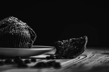 Siyah beyaz fotoğraf, sade anahtar, ev yapımı lezzetli çikolatalı kek, hamur işleri, ahşap bir yüzeyde beyaz bir kasede çörekler, yakın çekim. Lezzetli hamur işleri kavramı