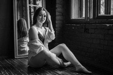 Uzun saçlı, beyaz gömlekli genç bir kız bir sandalyeye oturur ve düşünceli bir şekilde yüzünü çevirir. Güzel bir kızın konsepti