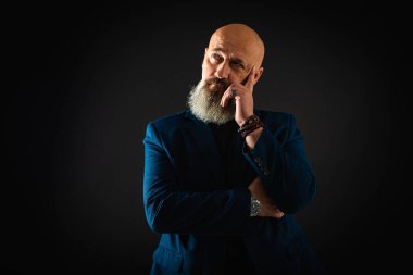 Sakallı, gülümseyen bir iş adamı. Elleriyle işaret ediyor. Bir şey gösteriyor. Alçakgönüllülük. Portre çok duygusal.