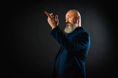 Sakallı, gülümseyen bir iş adamı. Elleriyle işaret ediyor. Bir şey gösteriyor. Alçakgönüllülük. Portre çok duygusal.