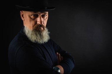 Genç, yakışıklı, duygusal, ciddi bir adamın portresi. Gri uzun sakallı, siyah şapkalı, karanlık bir arka planda izole edilmiş. Yazıtlar için bir yer var.