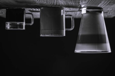 Siyah beyaz fotoğraf, sütlü kahve macchiato americano ve bir bardak kahvenin içinde katmanlar dolusu kahve. Ahşap arka planda bir fincan kahve, yan manzara. Alçakgönüllülük. Seçici odaklanma. Ters ufuk çizgisi