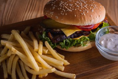 Ahşap zemin üzerinde pişmiş et, domates, soğan, peynir, marul ve patates kızartması dilimlenmiş hamburgerler. Lezzetli yemek kavramı