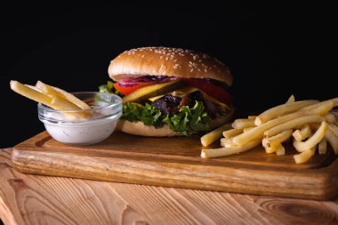 Ahşap zemin üzerinde pişmiş et, domates, soğan, peynir, marul ve patates kızartması dilimlenmiş hamburgerler. Lezzetli yemek kavramı
