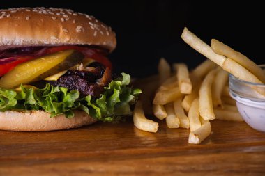 Ahşap zemin üzerinde pişmiş et, domates, soğan, peynir, marul ve patates kızartması dilimlenmiş hamburgerler. Lezzetli yemek kavramı