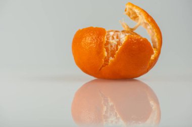 Tatlı, sulu mandalina. Bir kısmı hafif bir arka planda, yan görünüşte soyulmuş. Yüksek anahtar. Yazıtlar için bir yer var. Seçici odak 