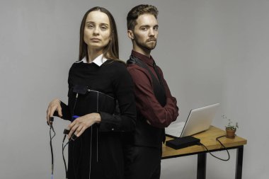 Konsantre, düşünceli bir kadın aydınlık bir odada, bir bilgisayar yalan makinesi üzerinde deneme yapıyor. Masada oturan genç adam yalan makinesi ve yalan makinesi monitörüne bakıyor. Doğruluk kavramı