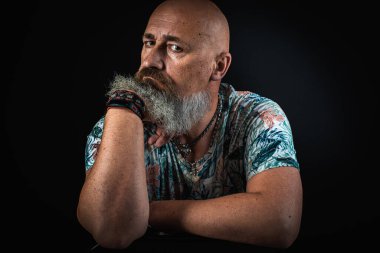 Vücut dili. Duygusal, yakın plan, duygusal, düşünceli, yakışıklı, sakallı genç bir iş adamının koluna yaslanmış portresi. Alçak tuş koyu arkaplanda izole edildi