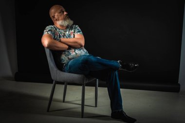 Yakın plan, duygusal, düşünceli, yakışıklı, sakallı bir iş adamının portresi. Alçak tuş koyu arkaplanda izole edildi. Vücut dili