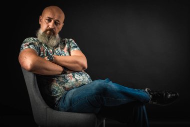 Yakın plan, duygusal, düşünceli, yakışıklı, sakallı bir iş adamının portresi. Alçak tuş koyu arkaplanda izole edildi. Vücut dili