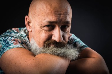 Vücut dili. Duygusal, yakın plan, duygusal, düşünceli, yakışıklı, sakallı genç bir iş adamının koluna yaslanmış portresi. Alçak tuş koyu arkaplanda izole edildi