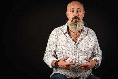 Yakın plan, duygusal, düşünceli, yakışıklı, sakallı genç iş adamının portresi. Alçak tuş koyu arkaplanda izole edildi. Vücut dili