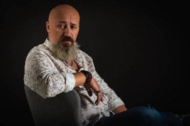 Yakın plan, duygusal, düşünceli, yakışıklı, sakallı genç iş adamının portresi. Alçak tuş koyu arkaplanda izole edildi. Vücut dili