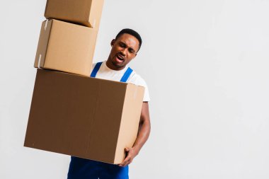 Beyaz tişört ve mavi pantolon giyen bir teslimatçı elinde kutular tutuyor. Beyaz bir arka planda izole edilmiş. Teslimat, posta, sevkiyat, yükleyici, kurye. Kutuyu kapat. İşaret dili