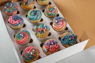 Açık bir yüzeyde sarı, mavi ve pembe renkli matte kekleri. Seçici odaklanma. Doğum günü veya Noel pastası, tatil.