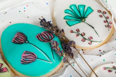 Tatlı, lezzetli, renkli ve zencefilli kurabiyeler hafif bir arka planda lavanta filizi ile boyanmış. Tatlı çok tatlı. Seçici odaklanma. Tatlı ve yemek pişirme kavramı