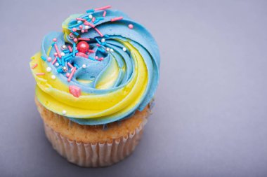 Rengarenk kremalı kekleri kapayın, renkli yıldızlı süslemeler, lezzetli ve muhteşem. Gri arkaplandaki üst görünüm. Doğum günü kavramı, kutlama, tatlı.