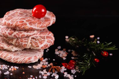 Koyu arkaplanda çiğ pirzola ile hamburger. Alçakgönüllülük. Etoburlar, et yemekleri. Seçici odak