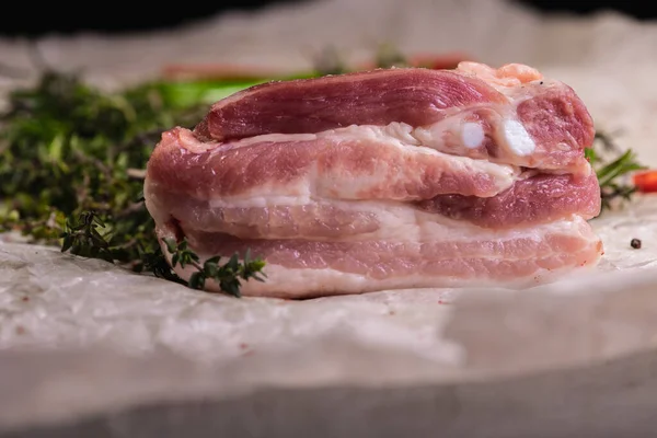 Raw fresh beef ribs steak with seasoning on a light surface, parchment, before cooking. Seasoning for meat steak with ribs for eyes rosemary, coriander, pepper. Top view, lying flat