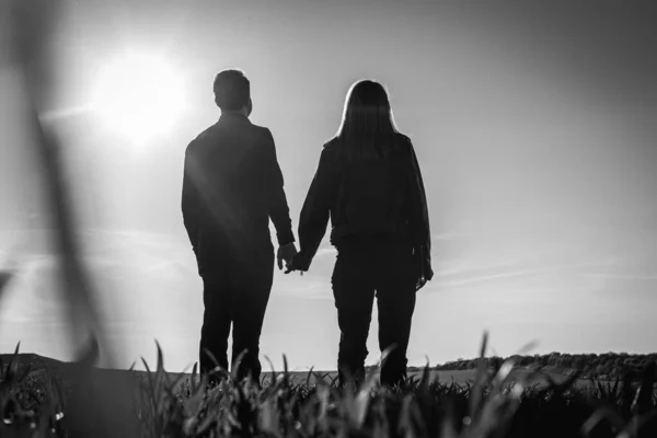若い夫婦が畑で夕日を楽しんでいます 鍵が低い 白黒写真 — ストック写真