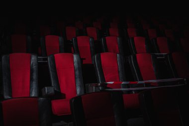 Sinema salonundaki kırmızı sandalyeler bir ışık demeti, basit bir anahtar, kısıtlayıcı bir bant ve karantina ile aydınlatılır. Seçici odaklanma. Boş sinema, COVID 19 karantinası, SARS-CoV-2, 2019-NCoV