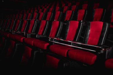 Boş sinema salonu. Sinema salonundaki koltuklar kırmızı ve siyah ışık huzmeleriyle aydınlatılır. Seçici odaklanma. Karantina, sandalyelerde kısıtlayıcı bant