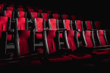 Boş sinema salonu. Sinema salonundaki koltuklar kırmızı ve siyah ışık huzmeleriyle aydınlatılır. Seçici odaklanma. Karantina, sandalyelerde kısıtlayıcı bant
