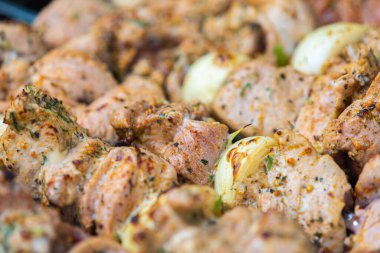 Barbeküde ızgara et şişleri yakın. Soğanlı domuz budu parçaları, şişlerin köşesinde kızartılmış.