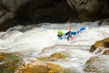 Yaremche şehri, Ivano-Frankivsk bölgesi, Ukrayna, 5 Haziran 2021. Yazın dağlarda tehlikeli ve huzursuz bir nehirde renkli bir kanoya atlamak. Dalgalar, aktif dinlenme, yüzme