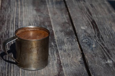 Gri-kahverengi bir yüzey üzerinde metal bir kupada bir fincan kahve, açık renk gölge, sabah kahvesinin güneş ışığı. Üst Manzara. Sabahları mis kokulu kahve.