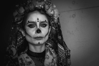 Mutlu Cadılar Bayramı konsepti. Korkunç bir kadın portresi, profesyonel makyajlı, korkunç görünüyor, siyah elbiseler, gri bir arka planda boş bir alanda, başka yöne bakıyor.