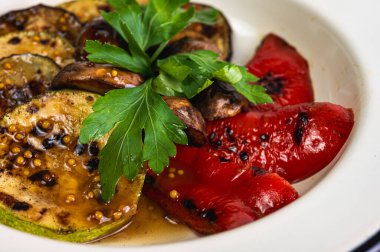 Izgara sebze çeşitleri: kabak, mantar, kırmızı dolmalık biber, taze otlarla süslenmiş. Bir yaz masası için mükemmel sağlıklı bir aperatif ya da meze.