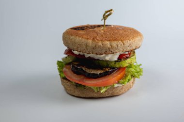Izgara sebzeli sulu vejetaryen burger (kabak, patlıcan, domates) ve taze marul. Modern yemek için sağlıklı, lezzetli ve iştah açıcı bir seçim.