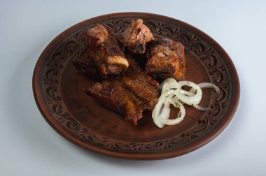Dört parça iştah açıcı ızgara et (shashlik / kebab) hafif bir arka planda sade ve süslü bir kil tabakta dilimlenmiş soğan halkalarıyla servis edilir.