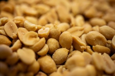 Kavrulmuş tuzlu fıstık yığının makro dokusu. Tuzlu kabuklu yerfıstığının yakın plan görüntüsü. Lezzetli biralar ya da sağlıklı vejetaryen yemekleri. Altın çıtır fındık yığını