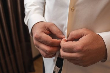 Mavi yeleği ilikleyen adamın ellerini kapat. Damat düğüne ya da resmi takım elbise giymiş iş adamına hazırlanıyor. Sabah hazırlama konsepti ayrıntıları
