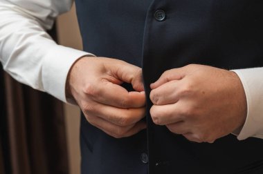 Mavi yeleği ilikleyen adamın ellerini kapat. Damat düğüne ya da resmi takım elbise giymiş iş adamına hazırlanıyor. Sabah hazırlama konsepti ayrıntıları