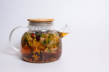 Beyaz arka planda sıcak bitkisel çay ve bambu kapaklı cam çaydanlık. Organik çiçek ve böğürtlen içeceği. Sağlıklı vitamin içeceği ve bağışıklık sistemi