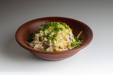 Taze salata, doğranmış lahana, yeşil bezelye, jambon ve taze soğan beyaz arka planda kahverengi seramik kasede. Sağlıklı yemek için nefis ev yapımı aperatif.