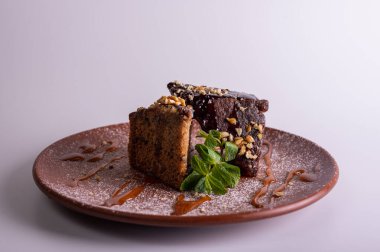 Çikolata jöleli ve kil tabakta naneli fındıklı kek dilimi. Ev yapımı ballı tatlı, ceviz ve karamel şurubu. Gurme tatlı pasta konsepti