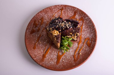 Çikolata jöleli ve kil tabakta naneli fındıklı kek dilimi. Ev yapımı ballı tatlı, ceviz ve karamel şurubu. Gurme tatlı pasta konsepti